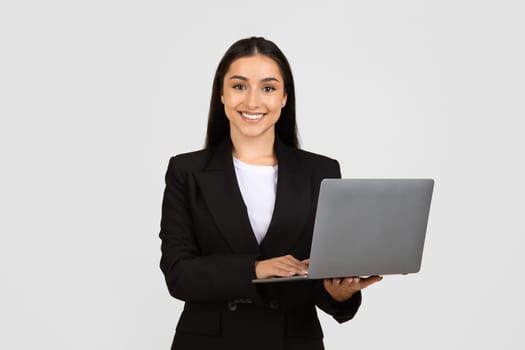 Professional young woman holding laptop with friendly smile