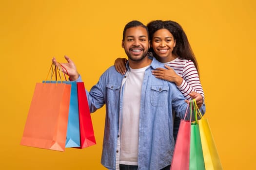 Happy Customers. Young Black Couple With Colorful Shopping Bags Looking At Camera