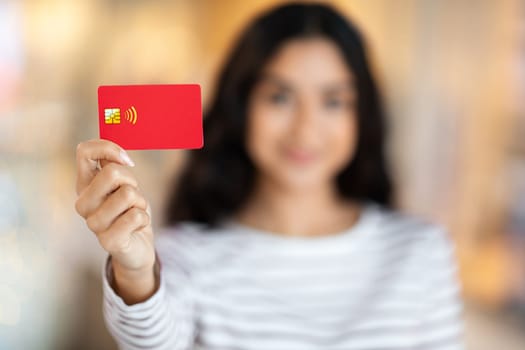 Red plastic credit card in young brunette woman hand