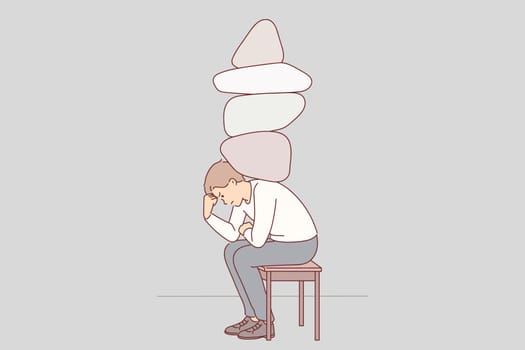Depressed man with stones on back experiencing stress and discomfort due to heavy workload
