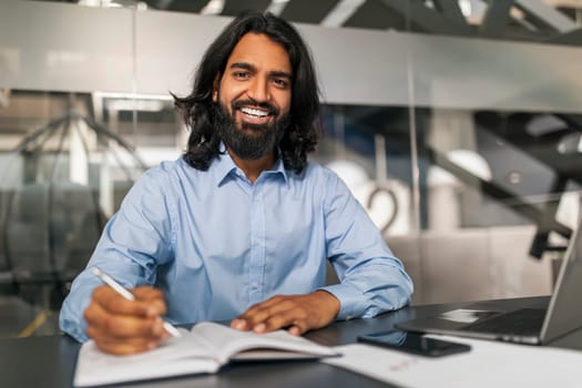 Positive young indian man employee working at office