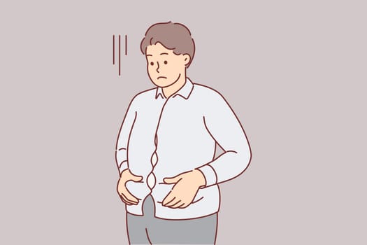 Overweight man is upset holding stomach, dressed in small shirt and needs to consult nutritionist
