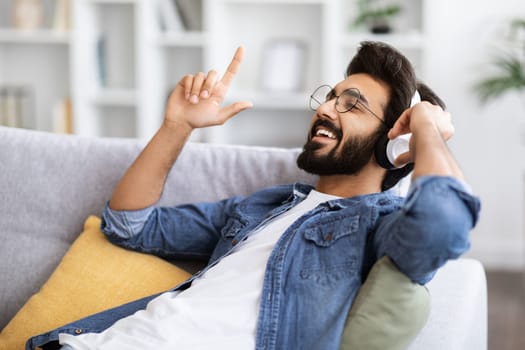 Positive Young Indian Man Having Fun While Listening Music At Home