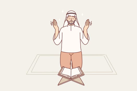 Muslim man prays on knees in front koran, observing islamic ritual during holy month of ramadan