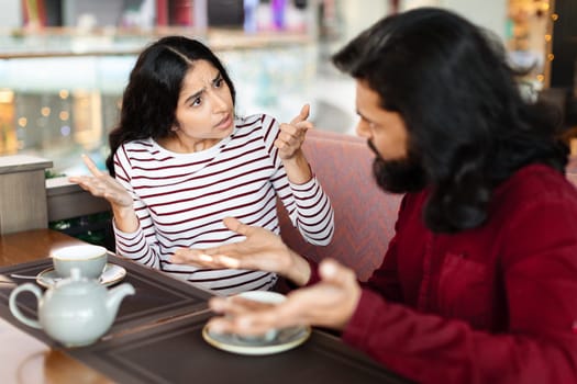 Unhappy young indian woman having conflict with boyfriend at cafe