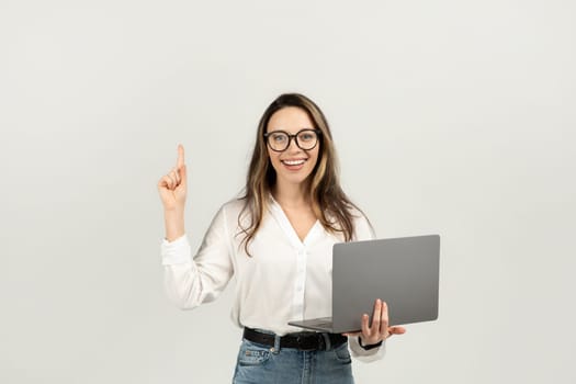 Intelligent young businesswoman with glasses holding a laptop in one hand
