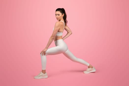 Focused and toned young woman in a white sports bra and leggings performing a stretching