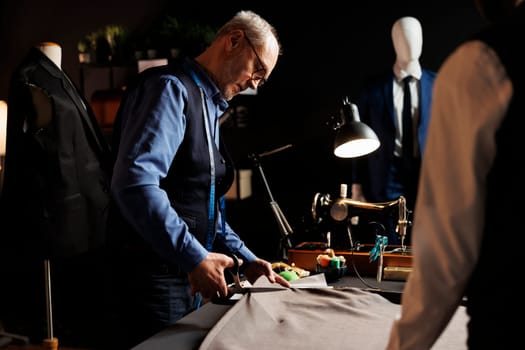 Suitmaker manufacturing suit in tailoring studio