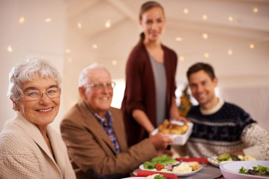 Grandmother, portrait and family at dinner on Christmas, together with food and celebration in home. Happy, event and people smile with lunch, dish and relax on holiday at table with grandparents