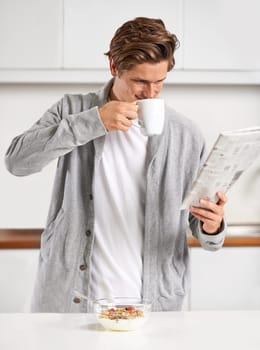 Coffee, breakfast and man with newspaper in kitchen for information at modern apartment. Nutrition, cereal and young male person drinking cappuccino or latte and reading journalism article at home.