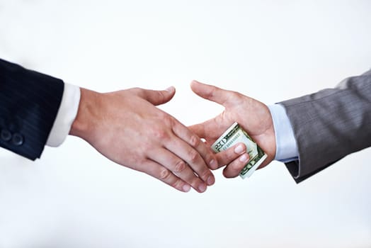 Business people, money and handshake with bribe for agreement or deal on a white studio background. Colleagues or employees shaking hands with cash, bills or paper for secret, bribery or fraud