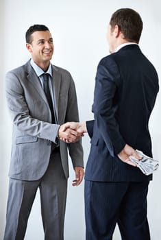 Happy businessman, money and handshake with bribe for agreement or deal on a white studio background. Man, colleagues or employees shaking hands with cash, bills or paper for secret, bribery or fraud