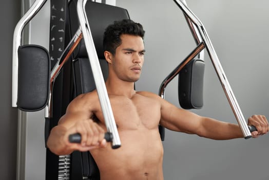 Workout, resistance exercise and man in gym for arm muscle training for health, wellness and strength. Active, body and young male athlete on machine with weights for bodybuilding in sports center.