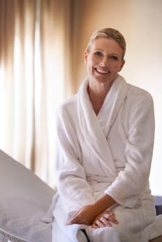 Woman, portrait and happy for spa treatment and wellness in robe, luxury and health on massage table or chair. Person or client relax, waiting and ready for holistic therapy, body and wellbeing