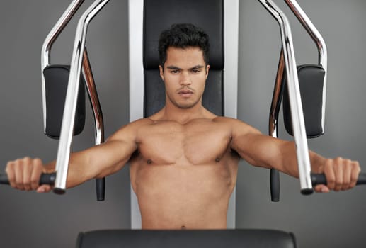 Sports, resistance exercise and man in gym for arm muscle training for health, wellness and strength. Portrait, body and young male athlete on machine with weights for bodybuilding in fitness center.