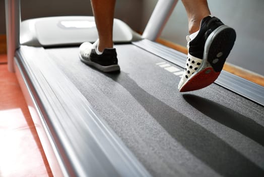 Fitness, feet and person running on treadmill in gym for health, wellness and body training. Active, shoes and closeup of athlete with workout or exercise on cardio machine at sports center.