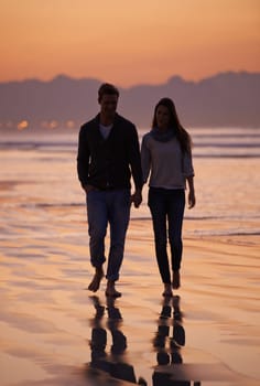 Couple, holding hands and walking on beach for sunset, nature and travel with bonding for love and commitment outdoor. People, trust and loyalty with adventure together for honeymoon or anniversary