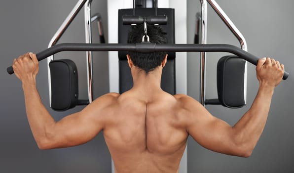 Exercise, pull down machine and man in studio on gray background for training or workout at gym. Back, health or shoulder press and body builder with equipment for wellness, strength or power