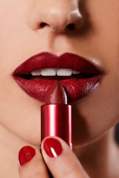 Closeup, woman and red lipstick with nails and makeup for beauty, application of cosmetics and shine. Lipcare product, bold color and manicure with mouth, face and skin for cosmetology with glow