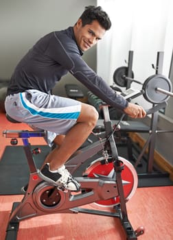 Fitness, bicycle and portrait of man in gym for cycling marathon, race or competition training. Fitness, health and athlete riding spinning machine for cardio workout or exercise in sports center.