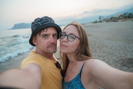 Happy couple taking a photo on a beach at the sea in Alanya city, Turkey. Travelling or vacation concept
