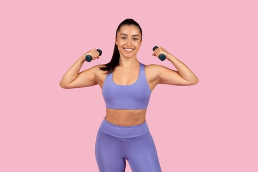 Strong woman flexing muscles with dumbbells