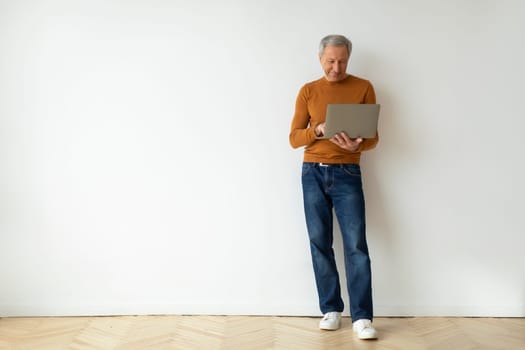 Grandfather with laptop in his hands over white wall background