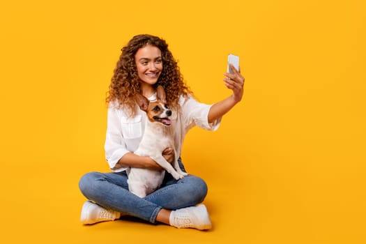 Curly-haired woman takes selfie with her joyful Jack Russell