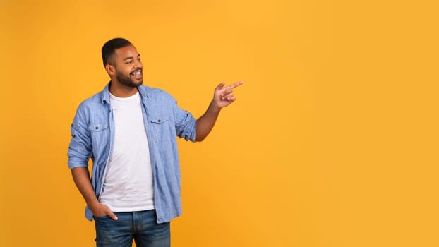Happy african american man in casual clothes pointing to the side