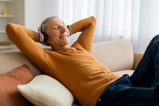 Joyful elderly man listening to music at home