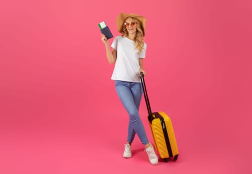 Blonde woman with sunglasses and luggage holding passport, pink background
