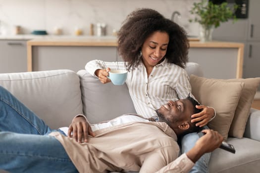 Relaxed African American couple cuddling on sofa in living room