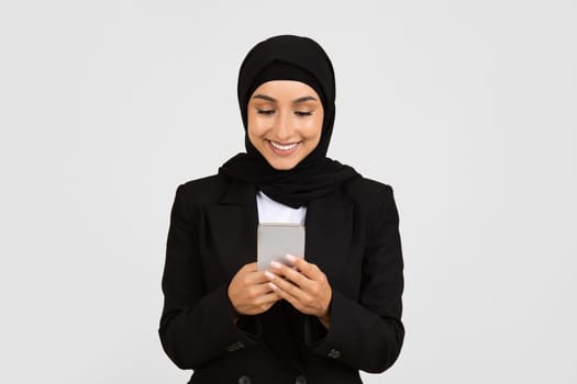 Content businesswoman in hijab using smartphone and smiling