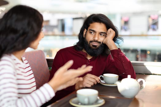 Young bearded indian man feeling bored at date at cafe