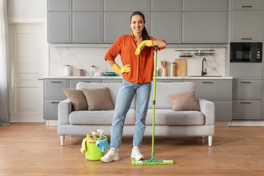 Happy woman with mop in modern, clean kitchen
