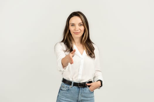 Approachable young woman with long brown hair, wearing a white blouse and jeans