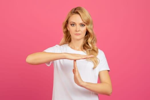 Determined Young Blonde Lady Showing Timeout Gesture Over Pink Background