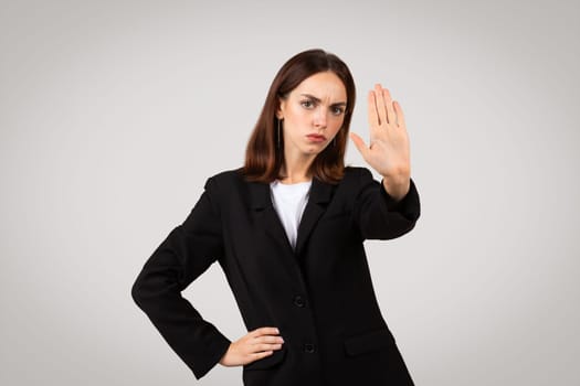 Stern young businesswoman showing a stop hand sign with a serious expression
