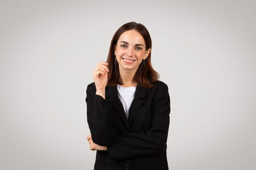 Smiling businesswoman with a confident look, pointing her finger up as if having a bright idea or presenting a solution