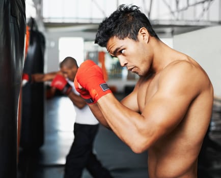 Punching bag, fitness and man with boxing gloves at a gym for training, resilience or performance. Sports, body and male boxer profile with punch practice for strength, energy for fighting exercise