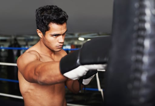 Sports, serious and man boxer in gym for exercise, workout and combat training for competition. Cardio, health and shirtless male athlete fighter in boxing ring with gloves in fitness center.