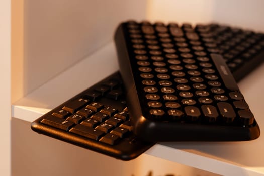 Two black wireless keyboards on a shelf