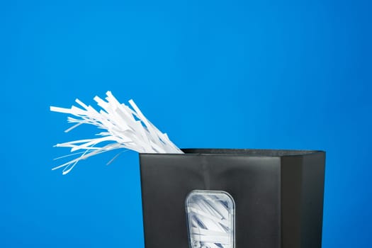 Office paper shredder on blue studio background