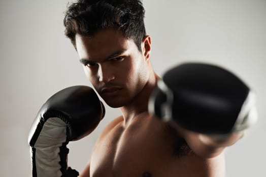 Man, serious and portrait with boxing gloves in studio for self defense, mma and combat. Male person, fighter and personal trainer for physical sport with commitment, focus and strong for activity