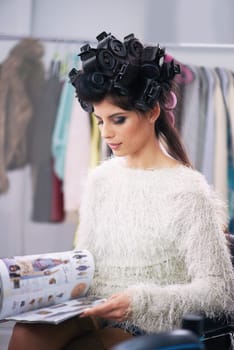 Woman, hair and makeup with curlers in salon, cosmetic care and model with magazine for treatment. Beauty, shampoo and girl backstage reading with hairdresser and styling, haircare and glamour