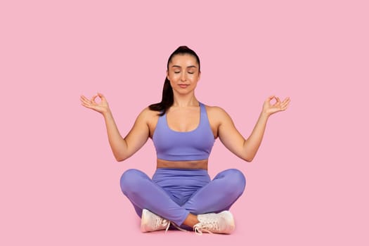Calm woman practicing meditation in purple outfit