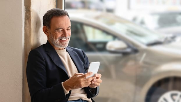Relaxed senior businessman with a friendly smile using his smartphone