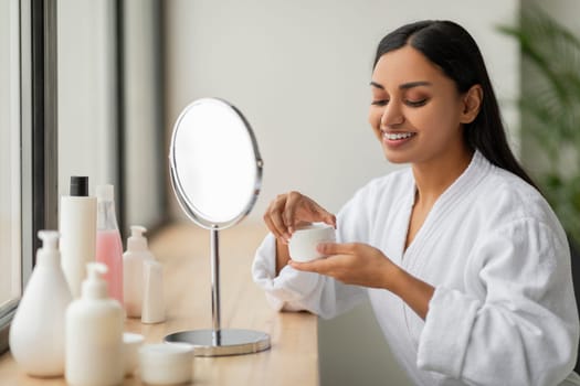 Portrait Of Attractive Indian Woman Applying Facial Cream At Bathroom