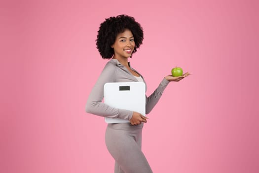 Healthy lifestyle concept with black woman holding scale and apple
