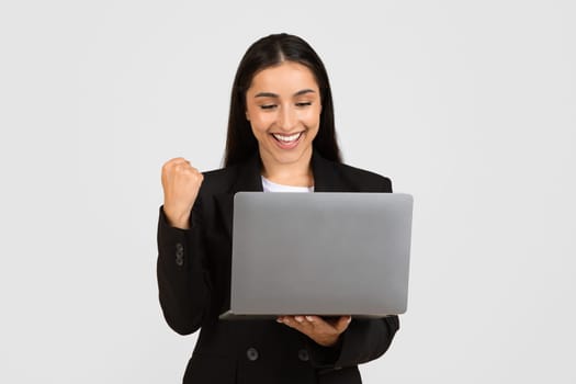 Joyful young businesswoman with laptop celebrating success